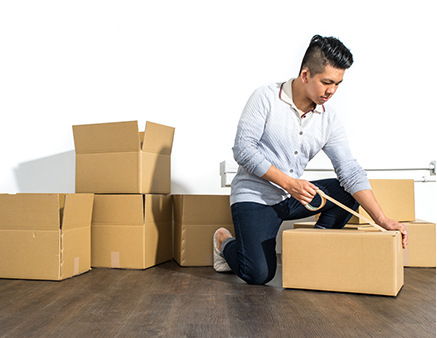 A man taping a moving box